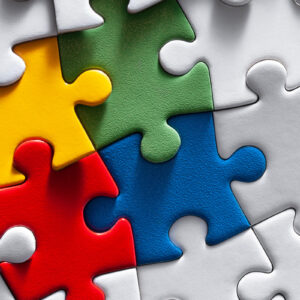 Colourful puzzle with yellow green, blue and red pieces surrounded by white.