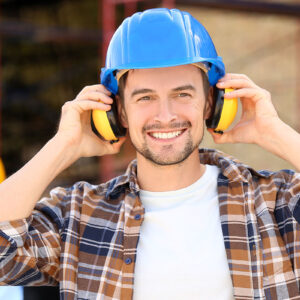 A man wearing ear protection and a hard hat, ensuring safety in a noisy and hazardous environment.