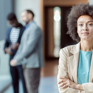 A woman standing in front of the camera with people in the background.
