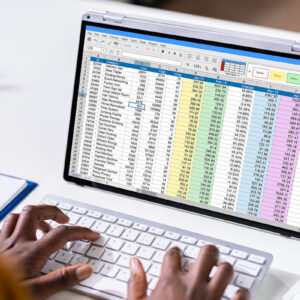A person typing on a keyboard and working on spreadsheet doc.