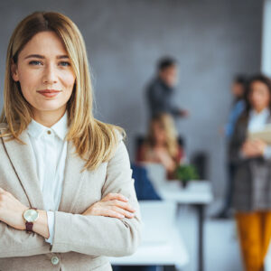 A professional woman in a business suit standing in front of a group, presenting herself as a leader.