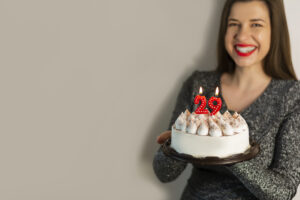 Smiling woman celebrating her birthday with a cake with number 29 candles